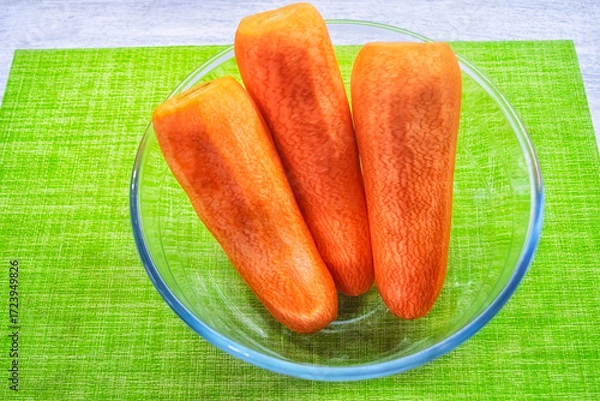 Fototapeta Washed and peeled carrots in a transparent plate.