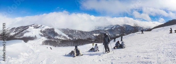 Fototapeta Panoramic winter landscape of a mountain ski resort with people relaxing on a slope (Maiko, Minamiuonuma, Niigata, Japan)