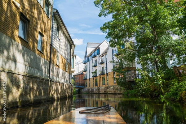 Fototapeta Riverside apartments along the river Stour in Canterbury, Kent. The front of a punt can be seen in the foreground.