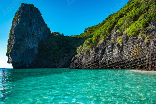 Fototapeta Nui Beach in Krabi, Thailand, features towering limestone cliffs covered in lush tropical vegetation embracing crystal clear turquoise waters, creating a secluded and picturesque island paradise