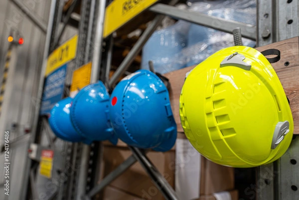 Obraz Kaski ochronne w magazynie przemysłowym – bezpieczeństwo pracy i BHP