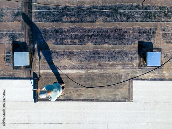 Fototapeta Roofer applying torch to bitumen membrane on torch down roof
