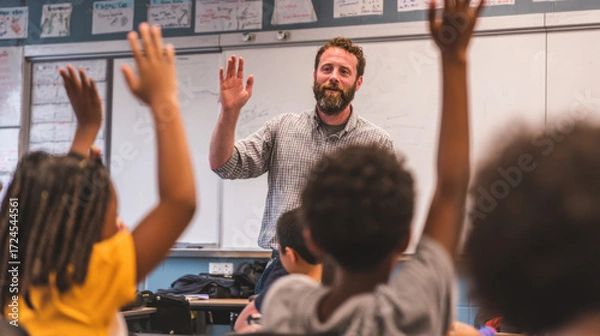 Obraz Enthusiastic teacher engaging with students in classroom setting with raised hands during lesson, promoting interaction and participation among children in learning environment