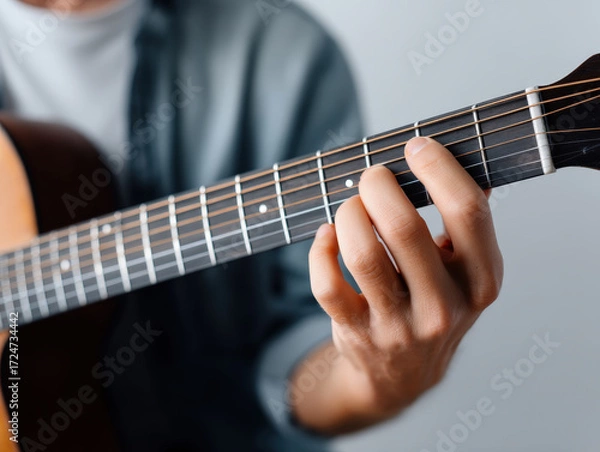 Fototapeta Close up of fingers tuning guitar strings with cozy indoor lighting and soft focus on fretboard for calm music moment