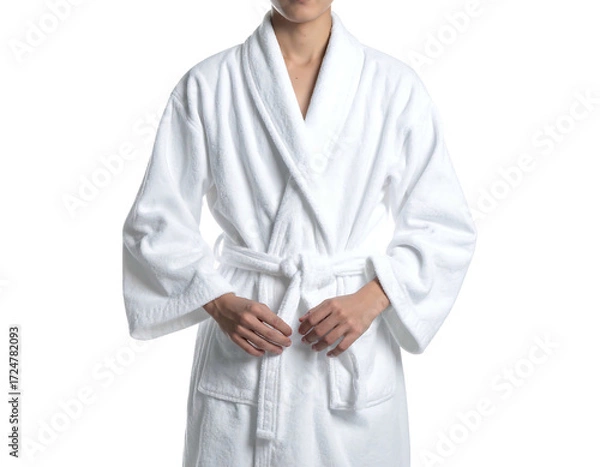 Fototapeta A person wearing a white bathrobe.  The robe is a simple, classic style with a V-neck, belted waist and long sleeves. The hands are holding the belt