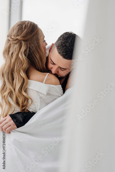 Fototapeta A gentle and romantic man and woman wrapped in a blanket on the windowsill