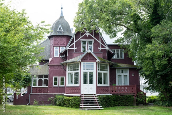 Obraz Historic red wooden villa with tower and large windows surrounded by trees