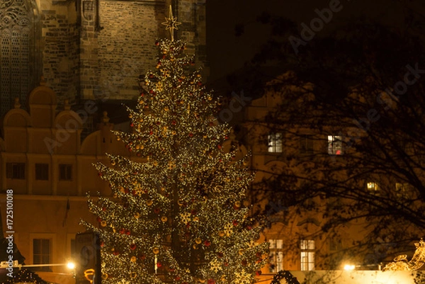 Fototapeta Christmas tree illuminated with lights at night, showing glowing decorations and festive atmosphere in a dark seasonal setting. Lifestyle