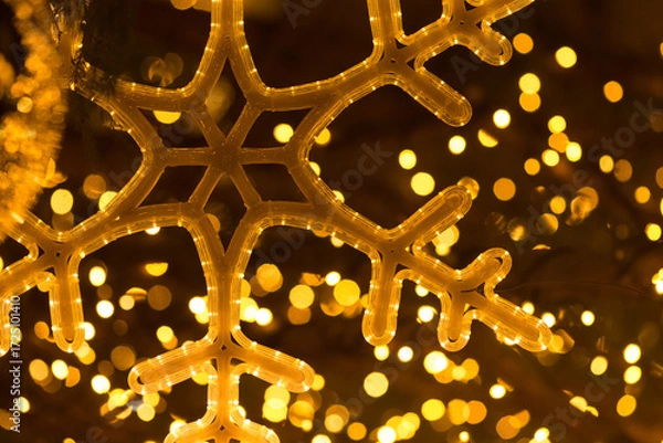 Fototapeta Glowing decorative snowflake in close up, used as a Christmas background element with festive illumination.