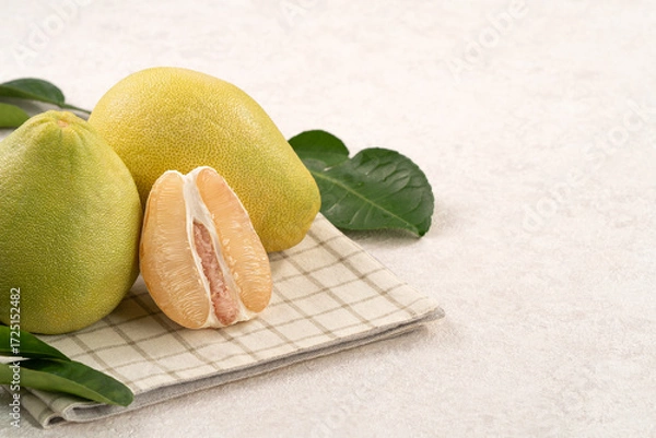 Obraz Fresh pomelo fruit with leaf on white table background.