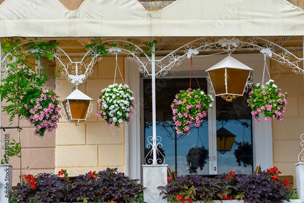 Fototapeta Balcony with hanging flower baskets, lanterns, and colorful decorative plants