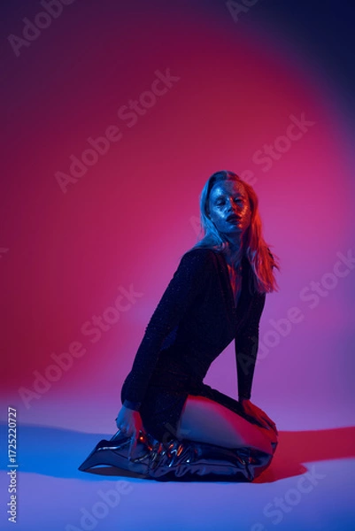 Fototapeta Blonde woman's glittering glow in studio lighting creates a captivating glamour scene