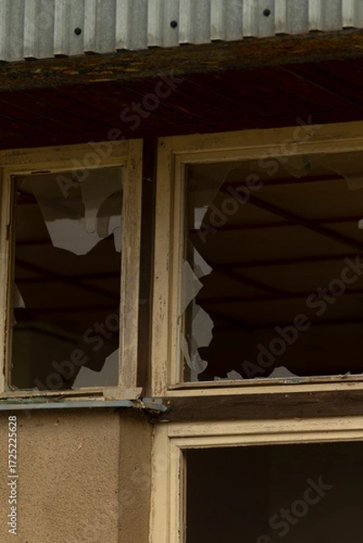 Fototapeta There is a broken window located on the side of a building that has experienced some form of damage or wear, disrupting its integrity