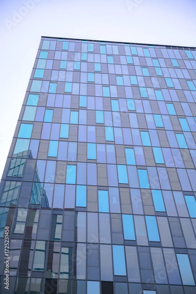 Fototapeta Modern architecture in Austria features a reflective glass facade contrasting with a clear blue sky