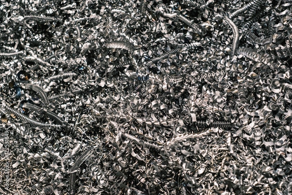 Fototapeta Shiny metallic machining shavings, close-up of curled steel swarf from industrial milling or turning processes in a workshop