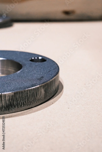 Fototapeta Close up of industrial metal ring component on beige surface, machined steel part for engineering and manufacturing background