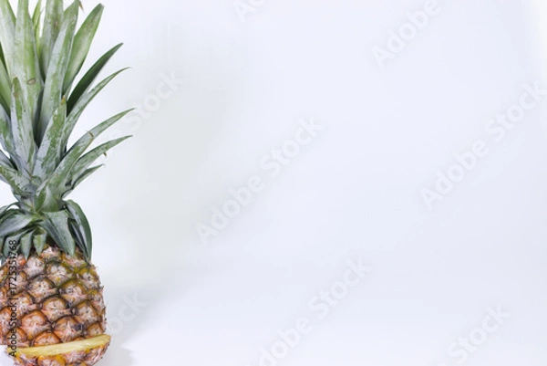 Fototapeta A Whole Pineapple with a Slice Cut Off on a White Background