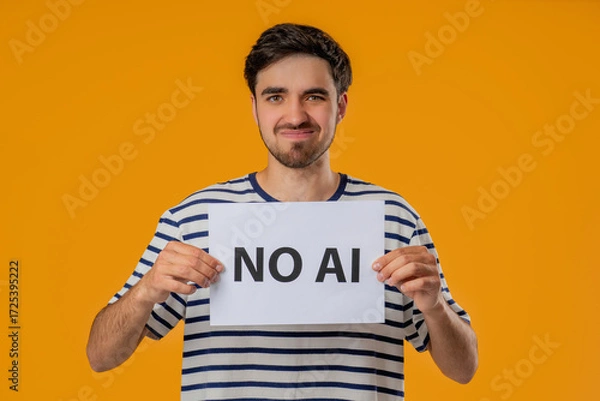 Fototapeta Young Man Holds Sign No Ai With Serious Face In Studio Visual Protest Against