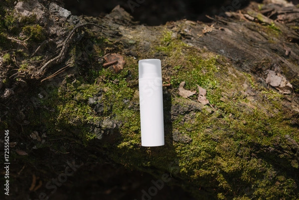 Fototapeta A dark and light glass serum bottle with a dropper, tree bark wood, moss. forest on a sunny day nature background. Concept of skin care, hydration, cosmetic demonstration eco-friendly product mock up
