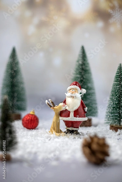 Fototapeta  Santa Claus toy figure with a reindeer on a festive snowy background. The concept of celebrating Christmas. Greeting card