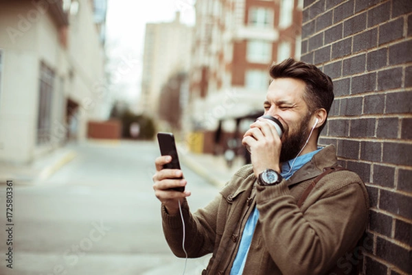Fototapeta Man enjoying coffee and using smartphone