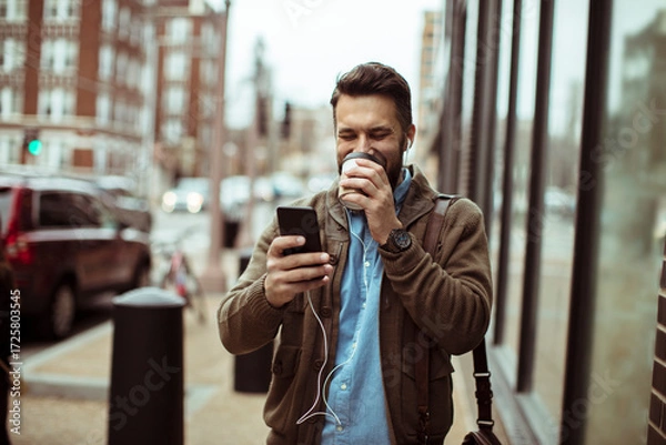Fototapeta Man enjoying coffee and using smartphone