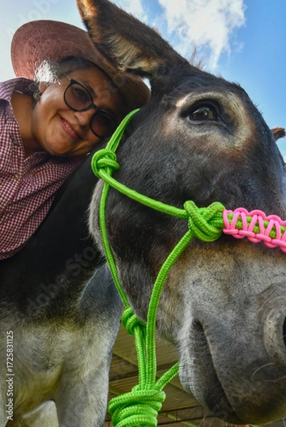 Fototapeta Rancher woman and a beautiful donkey pose for the camera.