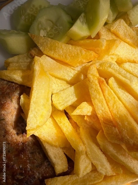 Fototapeta Prepared food: fried potatoes, sliced ​​fresh cucumber, steak. Close-up of a prepared portion of food on a white plate.