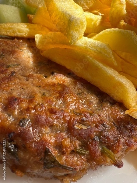 Fototapeta Prepared food: fried potatoes, sliced ​​fresh cucumber, steak. Close-up of a prepared portion of food on a white plate.