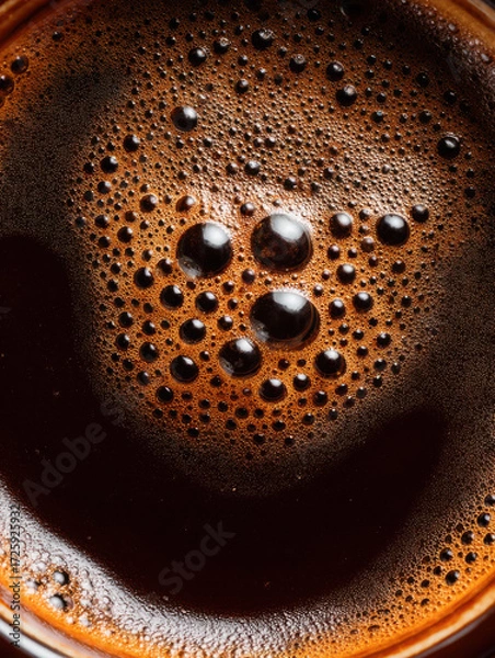 Fototapeta Dark coffee surface with bubbles reflecting light in a warm cup