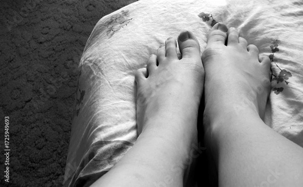 Fototapeta Black and white photo of bare feet resting on a patterned blanket, minimalistic composition, intimate and cozy atmosphere, suitable for themes of rest, mindfulness, or relaxation