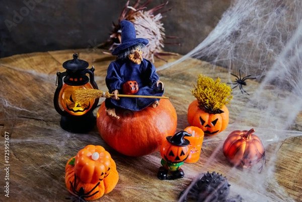 Fototapeta cute witch with a broom on halloween sits on a big pumpkin at a fun pumpkin party in the cobweb forest, All Saints Day, horizontal, creative focus