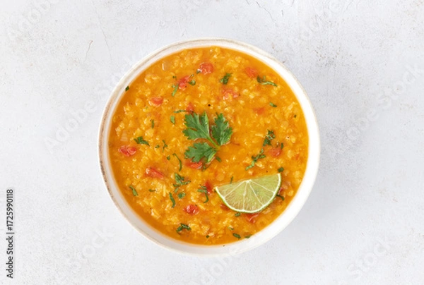 Fototapeta Red lentil soup with spices and fresh herbs on a gray background. Indian dal soup. Top view