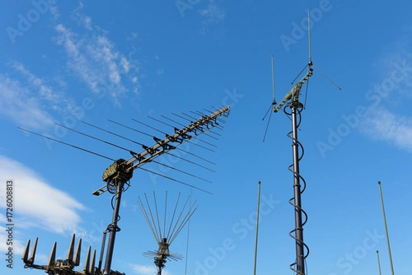 Fototapeta Various military antennas, transmitters and receivers for radio communication and transmission. Equipment, devices and technology used by signal corps. Blue sky as copy space.