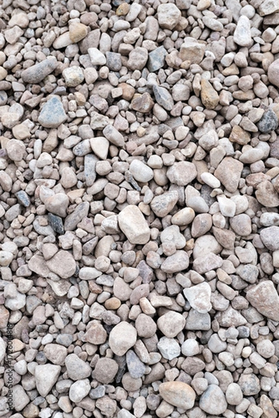 Fototapeta Textured surface of small gravel stones in various shades of gray and beige, creating a natural texture for landscaping, construction, or decorative purposes. Vertical background with copy space