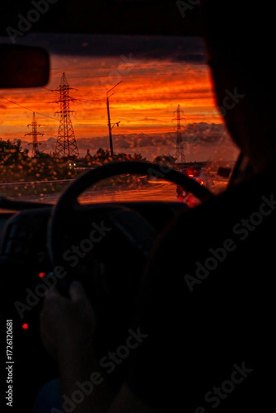 Fototapeta view from a car on the highway in bad weather conditions, rain and fog, at a beautiful red sunset