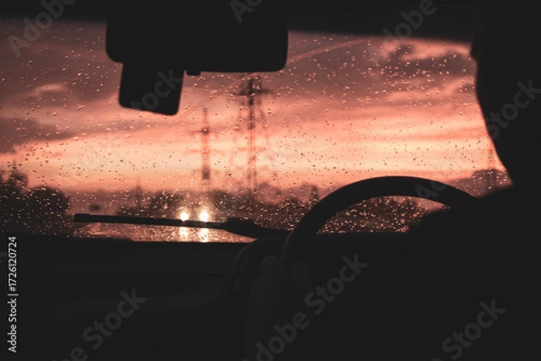 Fototapeta view from a car on the highway in bad weather conditions, rain and fog, at a beautiful red sunset