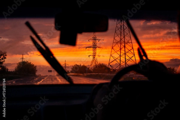 Fototapeta view from a car on the highway in bad weather conditions, rain and fog, at a beautiful red sunset