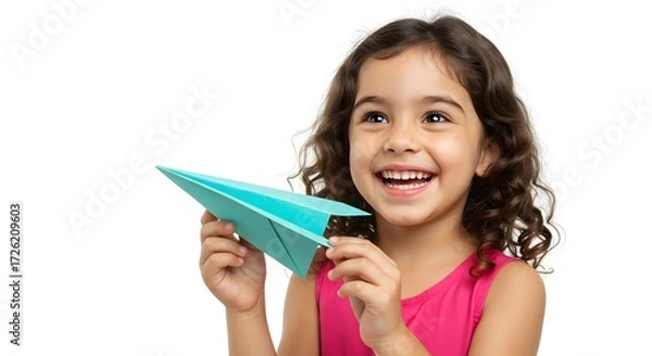 Fototapeta A young girl happily holding a paper airplane, with a big smile on her face. She's filled with joy and excitement as she prepares to launch her creation