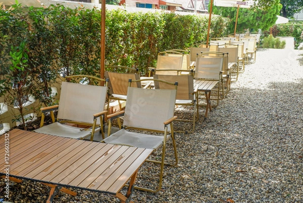 Fototapeta Colorful folding camping chair,wooden and chair set in garden on a sunny day,outdoor seating for restaurant or cafe.