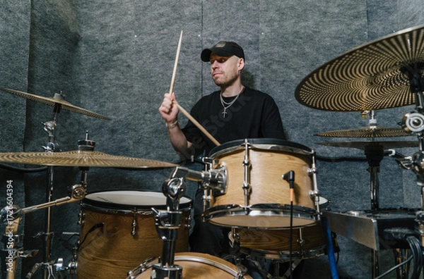 Fototapeta Drummer playing drums in soundproof studio room, practicing musical performance, producing rhythmic beats, creating music, working in professional environment, modern music industry concept.