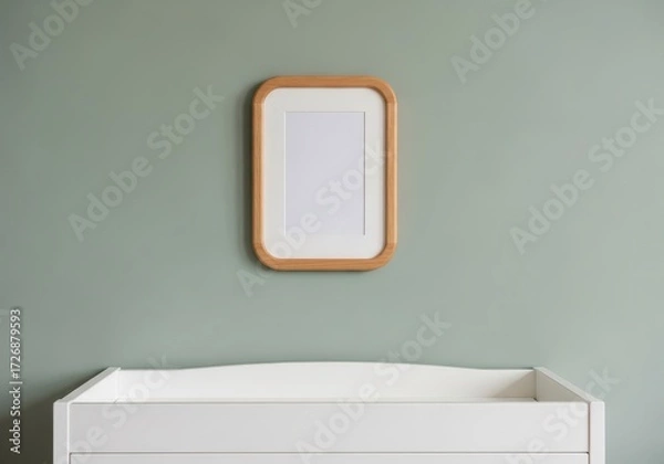 Fototapeta A minimalist photo frame hangs above a white changing table, creating a clean and organized nursery space