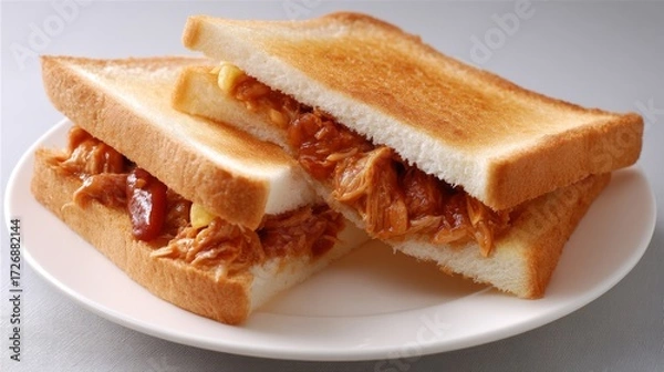 Fototapeta Sideangle shot of a toasted shredded meat sandwich on a white plate with plain background and studio lighting, showcasing crispy bread, savory filling, and appetizing textures with copy space for bra