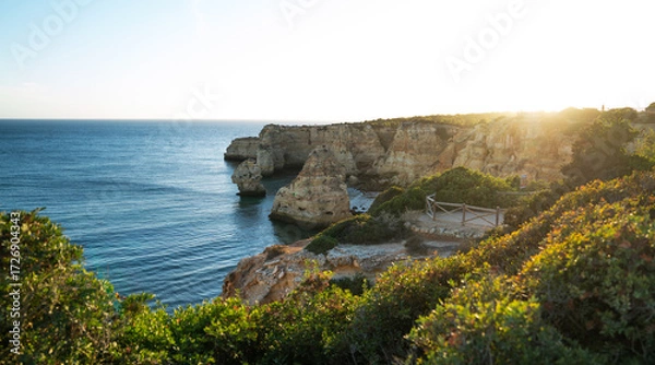 Fototapeta The golden rays of the setting sun illuminate the cliffs and serene coastal waters, casting a warm glow over the lush vegetation and secluded sandy coves of this picturesque Mediterranean landscape.