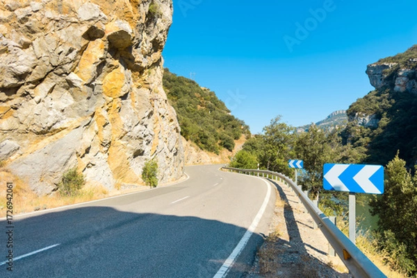 Fototapeta Scenic winding road by the Sobron reservoir in Burgos, Spain. A picturesque mountain road with curves surrounded by nature, green hills, and peaceful waters. High quality photo