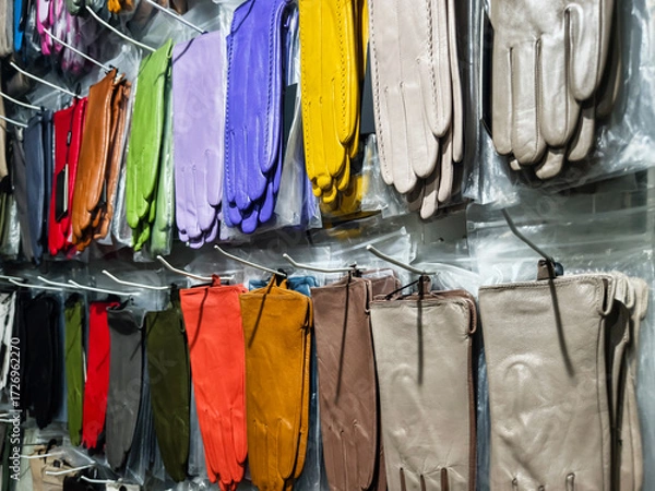 Fototapeta Colorful display of gloves hanging in a store showing a variety of styles and colors in an indoor shopping environment