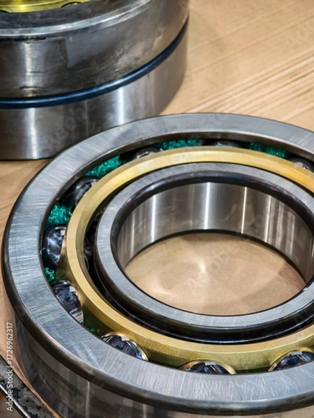 Fototapeta High-quality ball bearings displayed on a wooden surface with metallic components and green lubricant for industrial applications