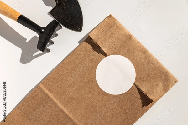 Obraz Gardening tool and brown paper bag with blank circle label on white background