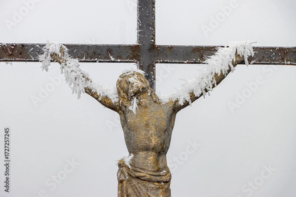 Fototapeta A winter crucifix with frost on a foggy background evokes themes of faith, suffering, and perseverance.