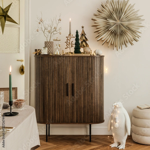 Fototapeta Stylish Christmas interior with wooden cabinet, festive greenery, candles, and decorative penguin lamp, creating a warm and joyful holiday mood.